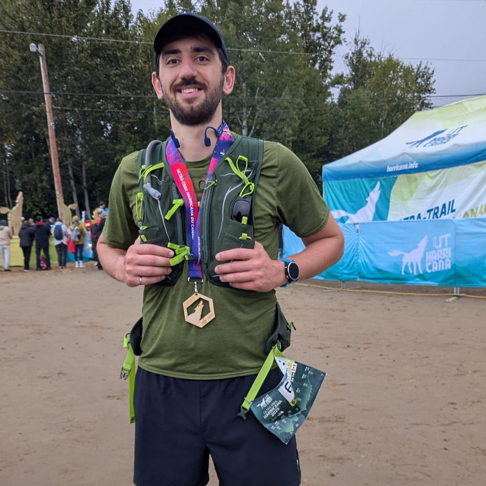 Matthew Behr exhausted after finishing his first ultra-marathon, wearing a wolf-shaped finisher medal